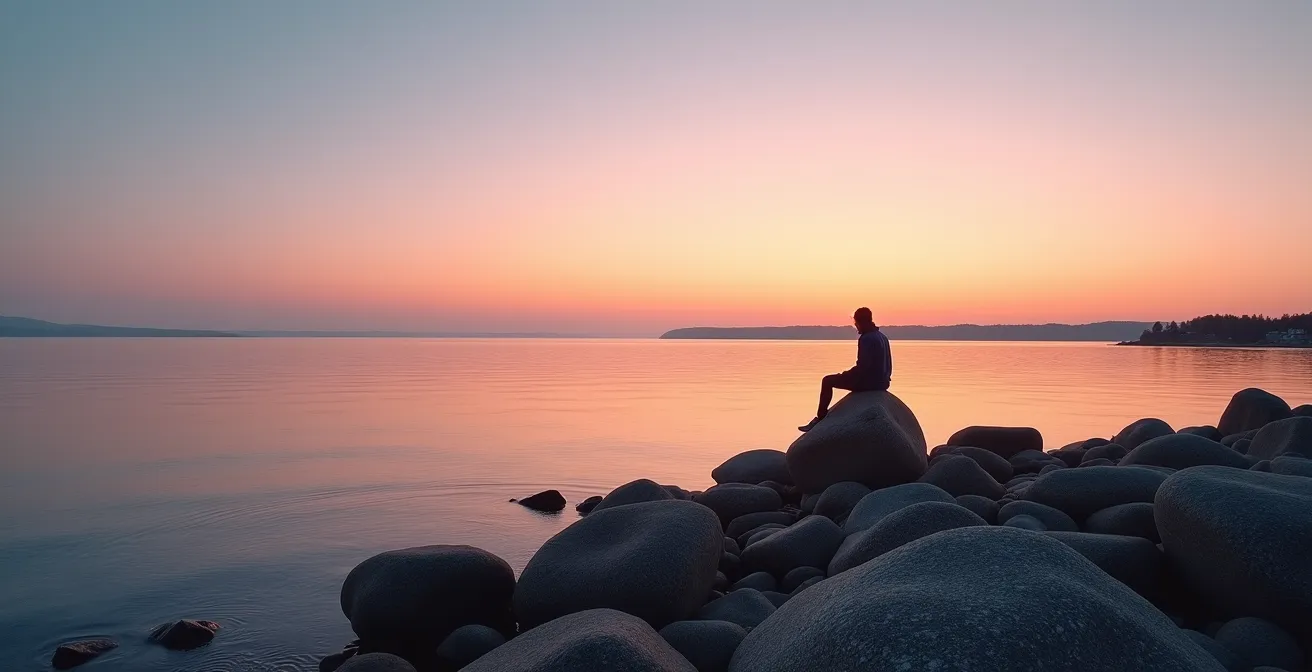 Personne assise seule sur un rocher face au fleuve Saint-Laurent au crépuscule